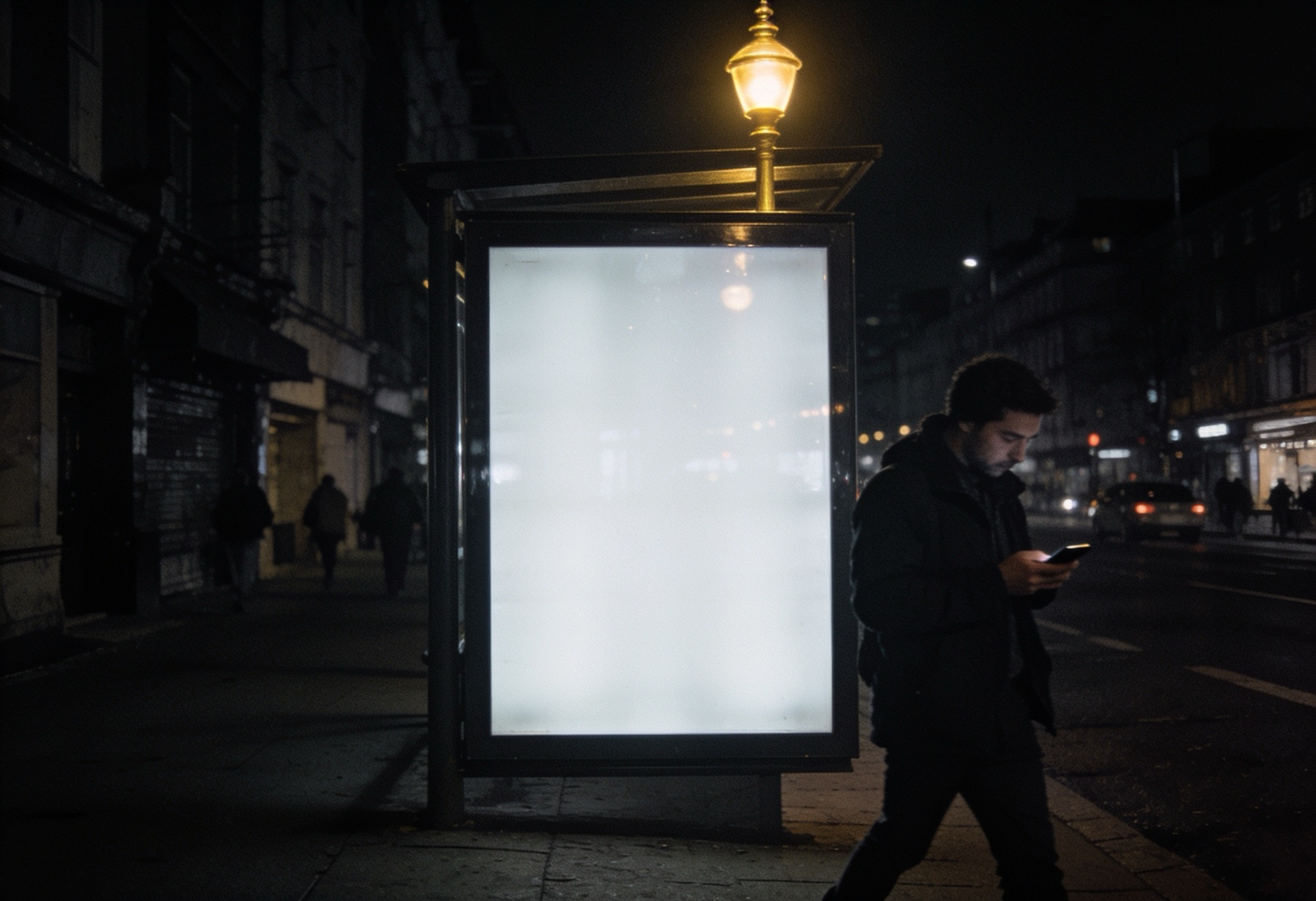 An empty, glossy billboard lit at night on a quiet street